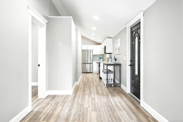 27 Prospect Ave, East Lyme, CT 06357 - kitchen with freestanding refrigerator, white cabinetry, light wood-style floors, vaulted ceiling, and decorative backsplash