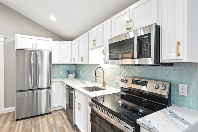 27 Prospect Ave, East Lyme, CT 06357 - kitchen featuring appliances with stainless steel finishes, a sink, vaulted ceiling, white cabinets, and light wood-style floors