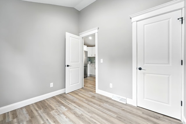 27 Prospect Ave, East Lyme, CT 06357 - unfurnished bedroom featuring freestanding refrigerator, light wood-type flooring, baseboards, and vaulted ceiling