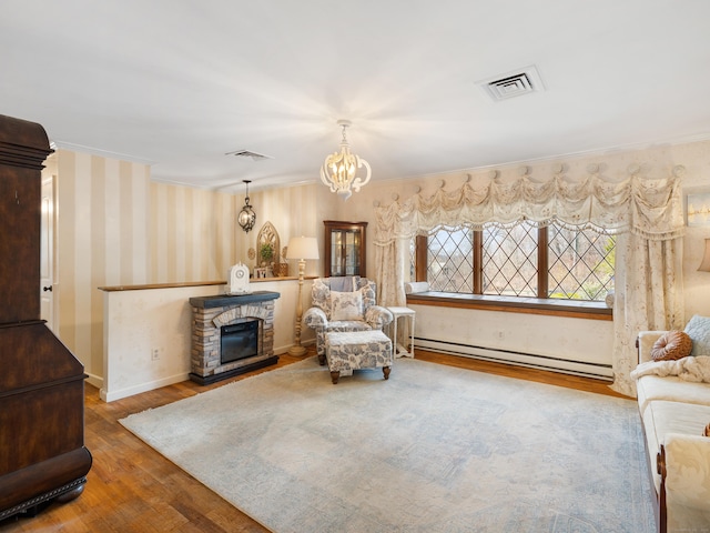 living area with a baseboard heating unit, ornamental molding, and wood finished floors
