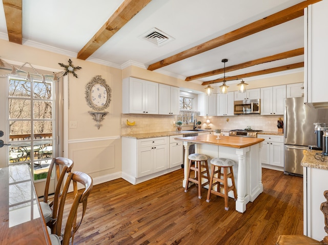 kitchen with visible vents, beamed ceiling, wood counters, appliances with stainless steel finishes, and white cabinetry