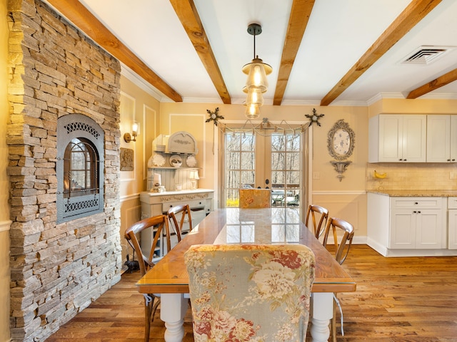 dining space with visible vents, ornamental molding, french doors, beamed ceiling, and light wood-style flooring