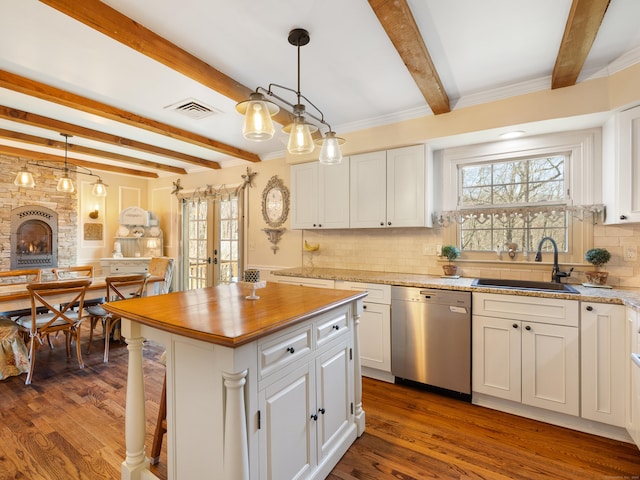 kitchen with visible vents, stainless steel dishwasher, a sink, beamed ceiling, and white cabinetry