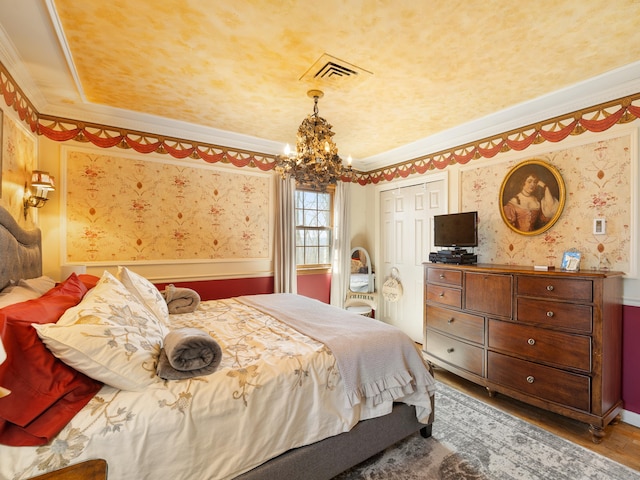 bedroom featuring wallpapered walls, wood finished floors, ornamental molding, and a notable chandelier