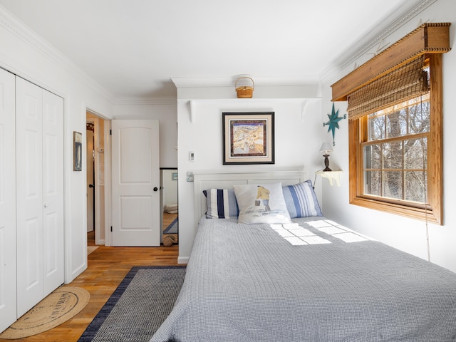 bedroom with wood finished floors, a closet, and ornamental molding