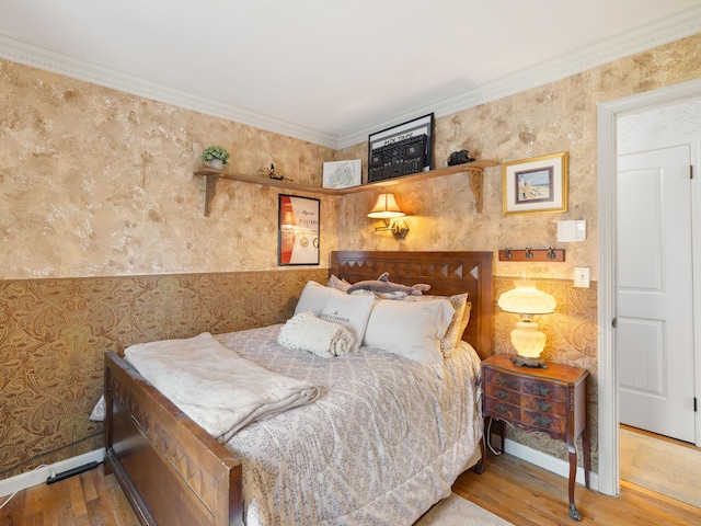 bedroom with wallpapered walls, wood finished floors, and crown molding