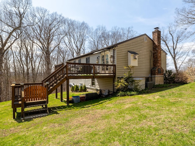 rear view of property featuring a chimney, a yard, and a deck