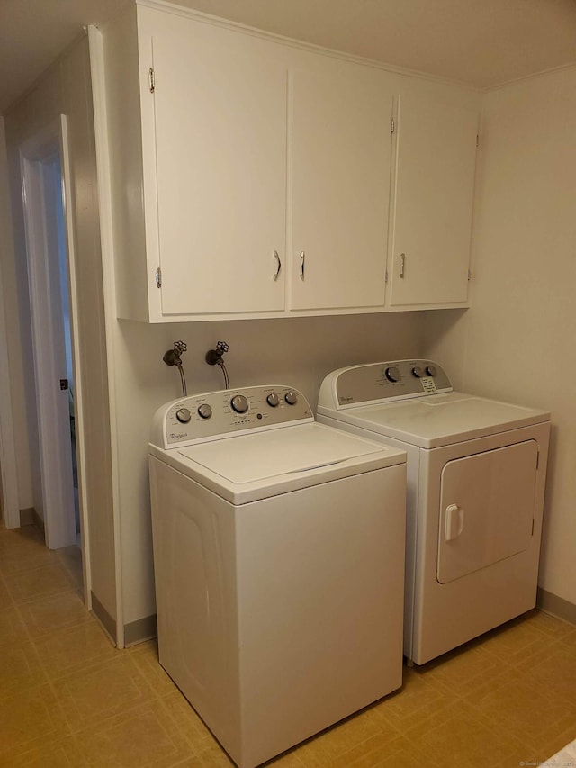 laundry room featuring independent washer and dryer, baseboards, light floors, and cabinet space