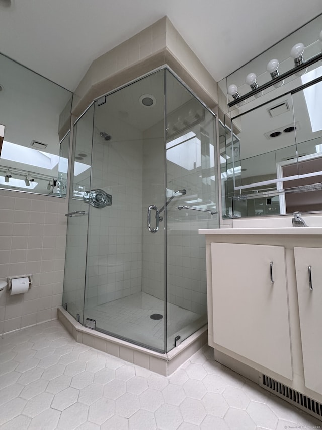 full bath featuring tile walls, a shower stall, tile patterned flooring, and vanity
