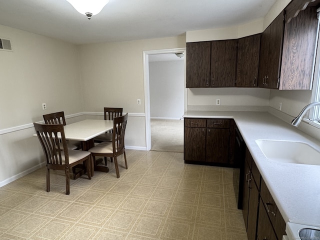 kitchen with a sink, light countertops, light floors, and dark brown cabinets