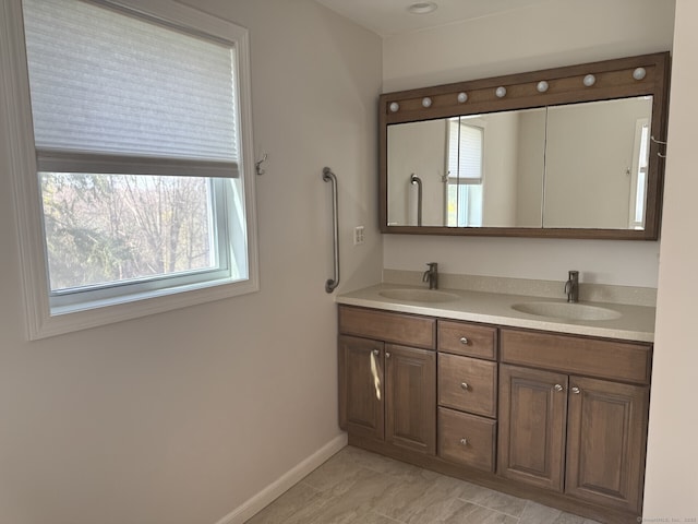 bathroom with double vanity, a sink, and baseboards