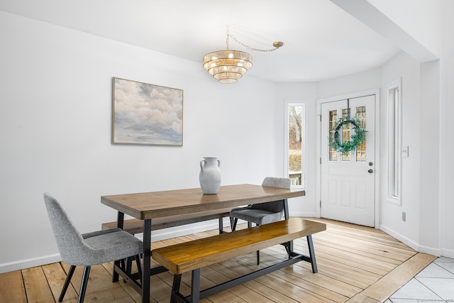 dining area with baseboards, an inviting chandelier, and light wood-style floors