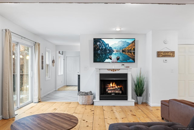 living area featuring hardwood / wood-style floors, baseboards, and a lit fireplace