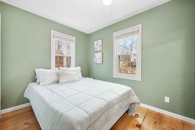 bedroom featuring wood finished floors, baseboards, and multiple windows