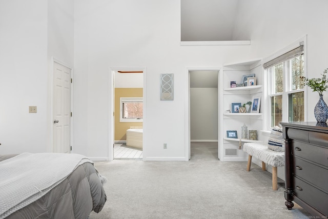 bedroom with a spacious closet, light carpet, a towering ceiling, and baseboards