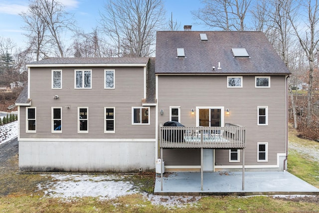 back of property with a deck, a chimney, and a patio