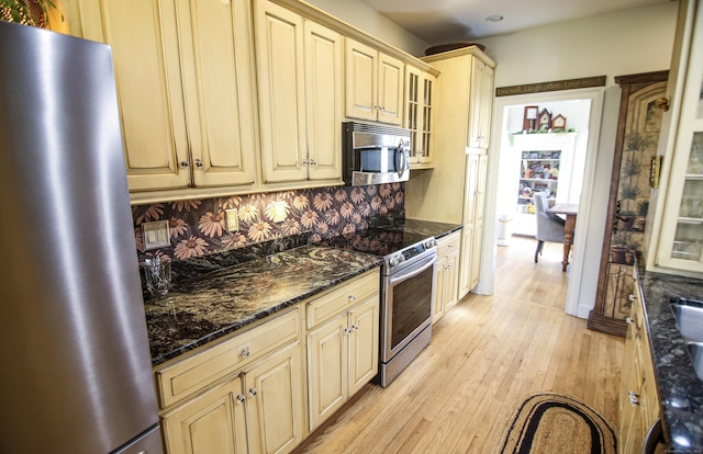 6 Rogers Dr, Stonington, CT 06355 - kitchen with stainless steel appliances, cream cabinets, light wood finished floors, glass insert cabinets, and dark stone counters