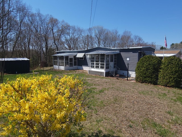 back of house with entry steps, a sunroom, and a lawn