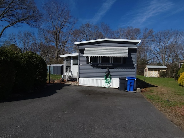 manufactured / mobile home with a storage unit, an outdoor structure, and a front yard