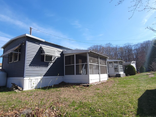 view of home's exterior featuring a sunroom and a yard