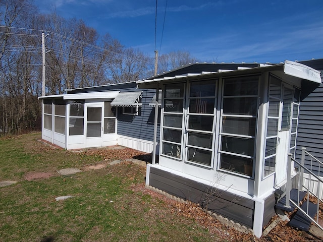 back of property with a sunroom and a lawn