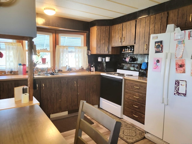 kitchen with backsplash, white appliances, light countertops, and a sink