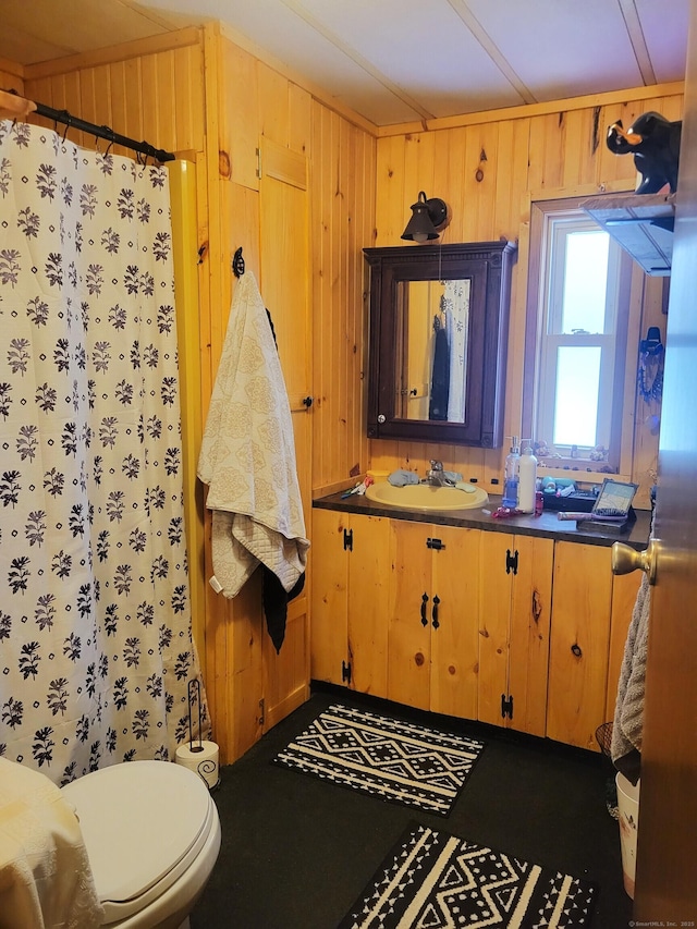 bathroom featuring wood walls, vanity, toilet, and curtained shower