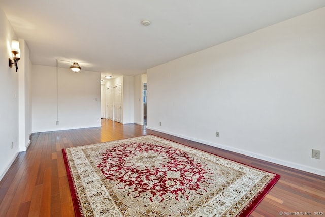 spare room featuring wood-type flooring and baseboards