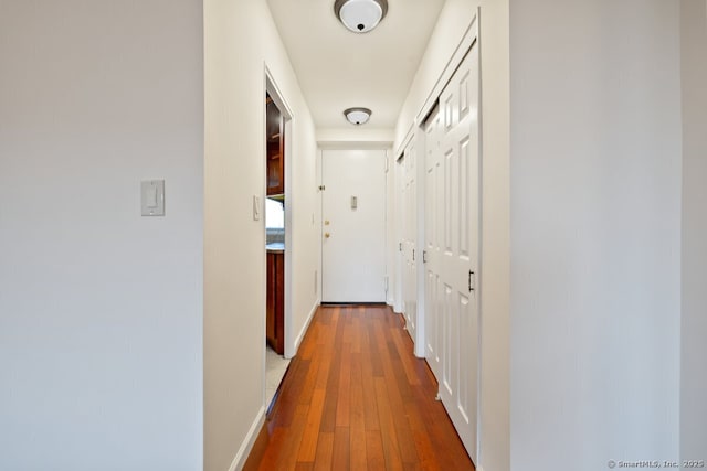 corridor featuring wood-type flooring and baseboards