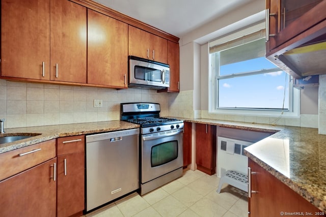 kitchen with brown cabinetry, a sink, backsplash, and appliances with stainless steel finishes