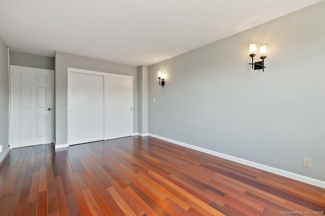 unfurnished bedroom featuring a closet, baseboards, and dark wood finished floors