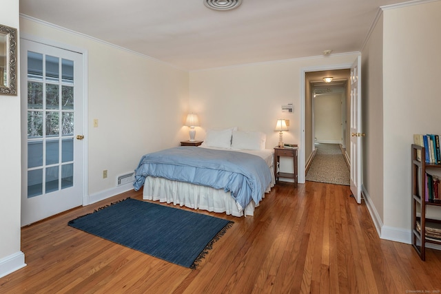 bedroom with baseboards, wood finished floors, and crown molding