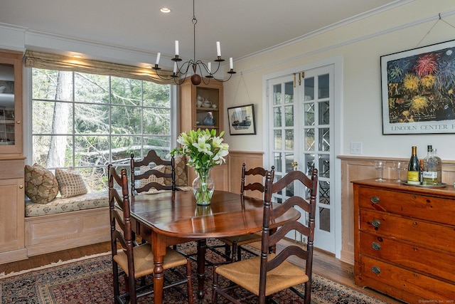 dining area with a wainscoted wall, wood finished floors, a chandelier, and crown molding