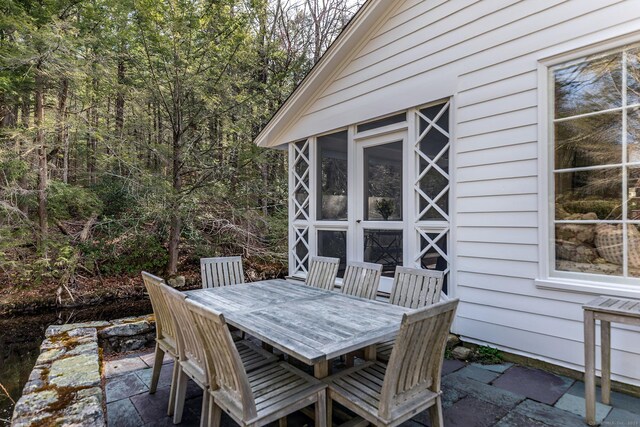 view of patio with a sunroom and outdoor dining area