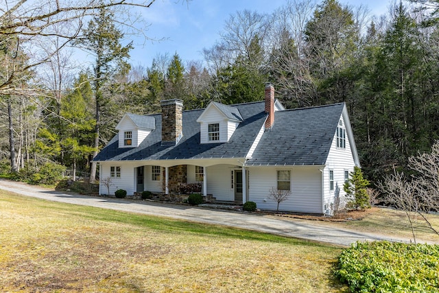new england style home featuring a front lawn, a porch, and a chimney