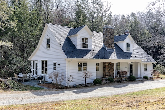 new england style home with a chimney and a porch