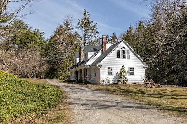 view of side of home with driveway and a chimney