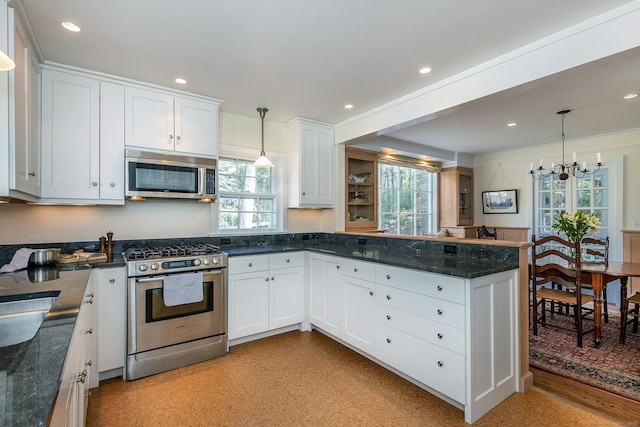 kitchen with a peninsula, plenty of natural light, appliances with stainless steel finishes, and white cabinets
