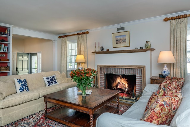 living room with visible vents, a fireplace, and ornamental molding