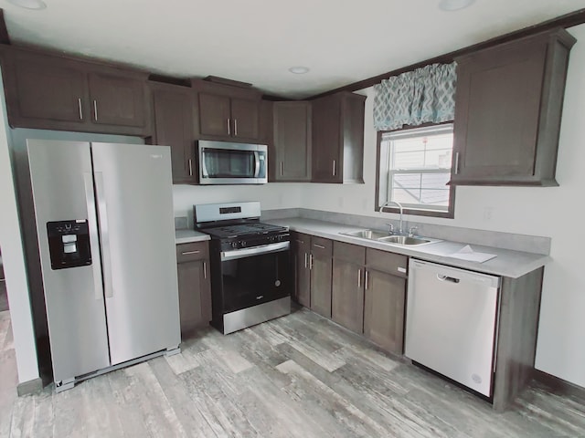 kitchen with light wood-type flooring, light countertops, dark brown cabinets, appliances with stainless steel finishes, and a sink