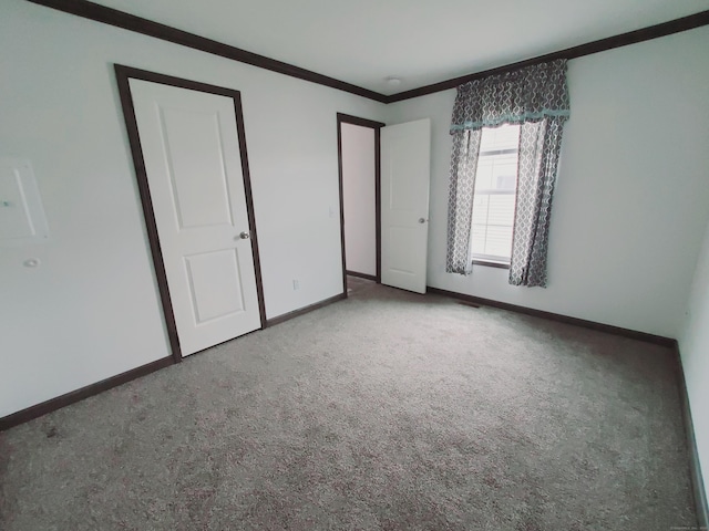 unfurnished bedroom featuring carpet, baseboards, and crown molding