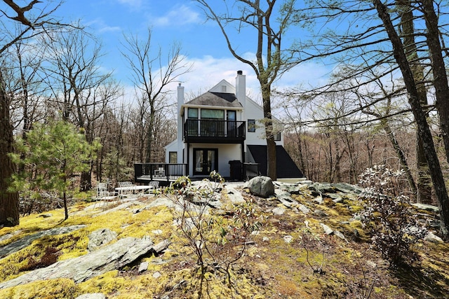 rear view of property with a wooden deck, french doors, a chimney, and a balcony