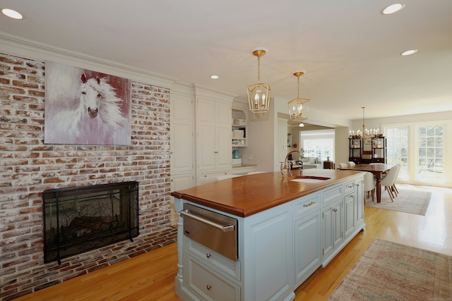 37 Giles Hill Rd, Redding, CT 06896 - kitchen featuring a brick fireplace, a sink, white cabinets, an inviting chandelier, and a warming drawer