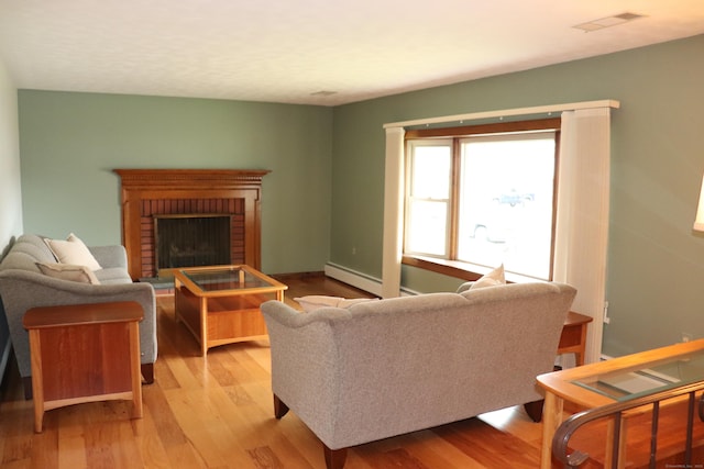 1 Sunrise Cir, Enfield, CT 06082 - living room with wood finished floors, a baseboard heating unit, a fireplace, and visible vents