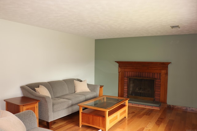 1 Sunrise Cir, Enfield, CT 06082 - living room featuring visible vents, a brick fireplace, wood finished floors, and a textured ceiling
