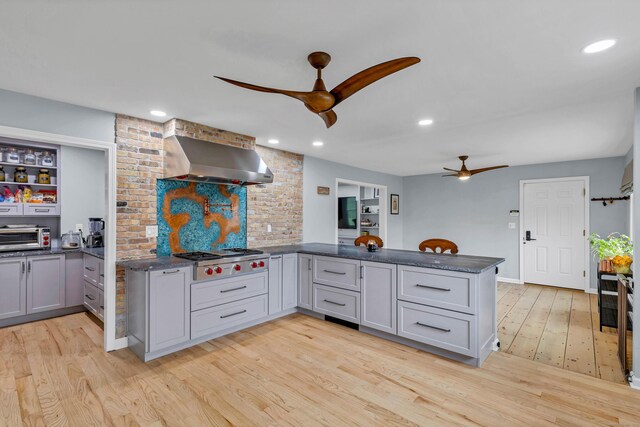 15 Briarwood Dr, Guilford, CT 06437 - kitchen featuring ceiling fan, stainless steel gas cooktop, wall chimney exhaust hood, a peninsula, and light wood-style flooring