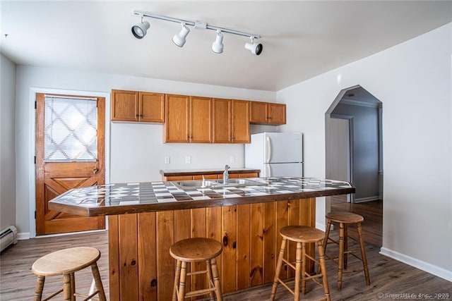 26 Columbia St, Ansonia, CT 06401 - kitchen featuring track lighting, baseboards, freestanding refrigerator, brown cabinetry, and dark wood-type flooring