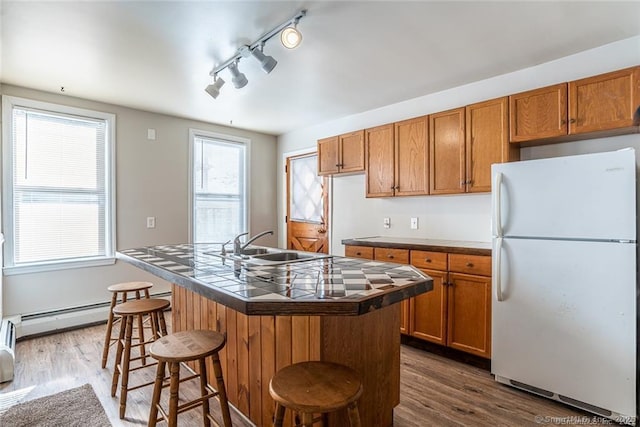 26 Columbia St, Ansonia, CT 06401 - kitchen featuring tile countertops, freestanding refrigerator, brown cabinetry, a breakfast bar, and a kitchen island with sink