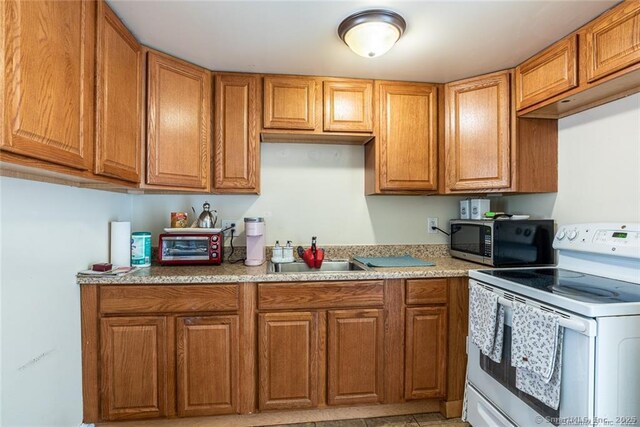 26 Columbia St, Ansonia, CT 06401 - kitchen with a sink, light countertops, electric stove, brown cabinetry, and stainless steel microwave