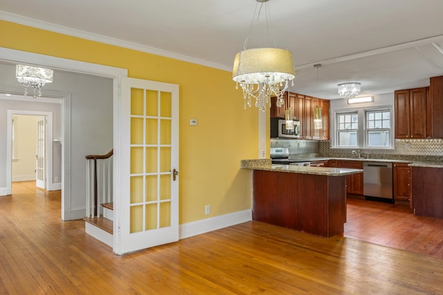 25 S Highland St, West Hartford, CT 06119 - kitchen featuring stainless steel appliances, a chandelier, hardwood / wood-style floors, a peninsula, and backsplash